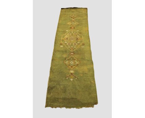 NARROW USHAK RUNNER Central West Anatolia, late 19th century, the olive green field centred by a medallion flanked by stylise