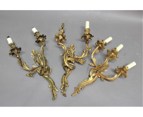 PAIR OF TWIN BRANCH GILT METAL WALL LIGHTS of rococo, foliate form, height excluding fittings 48cm, width 29cm; together with
