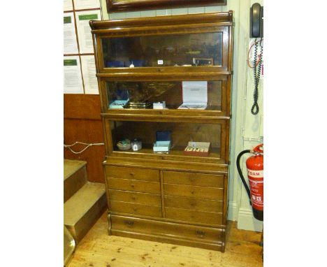 Oak Globe Wernicke bookcase having three glazed doors above four fall front drawers with a long drawer below