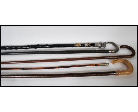 A collection of four walking stick canes to include an ebonised stick having a silver hallmarked collar with a horn handle, a