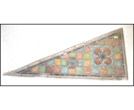 An early 19th Century leaded stained glass Arts and Crafts architectural panel of triangular / flag shape having flowerheads 