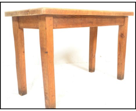 A vintage early 20th century chunky country pine scrub top dining table being raised on squared legs with fitted frieze and p