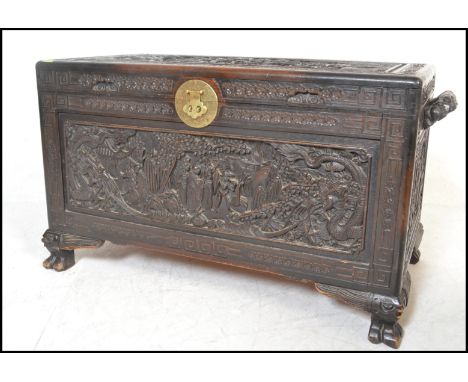 A good mid century 20th century Chinese camphor wood chest / trunk being carved in relief with dragons, figures among trees a