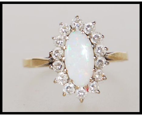 A hallmarked 9ct gold ring set with an oval cut opal with a halo of white stones. Marked with import marks for 1988. Weight 2