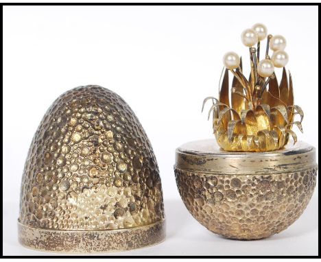 A silver hallmarked Stuart Devlin ' surprise egg ' having a textured exterior opening to reveal a silver plant set with pearl