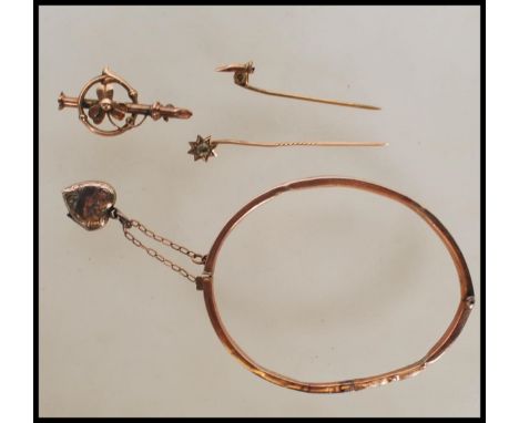 A hallmarked 9ct gold bangle with engraved foliate and swirl decoration, having hinged opening with tongue and groove clasp a
