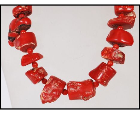 A vintage coral necklace consisting of threaded coral pieces with red bead spacers and stamped 925 silver hook and eye clasp.