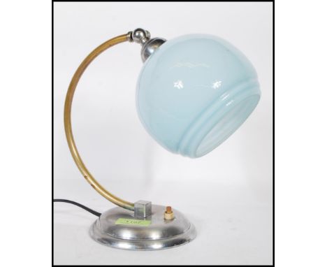 A Art Deco desk / table lamp, having a chrome circular base, brass bend support and a baby blue glass shade.