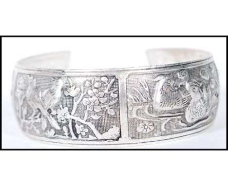 A 20th Century Chinese silver bangle bracelet having decorative repousse panels depicting birds and deer. Measures 7cm wide. 
