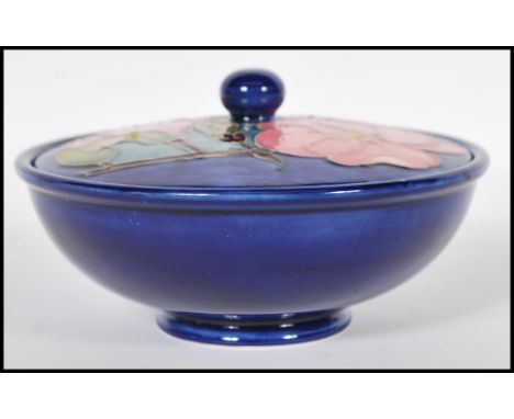 A vintage retro Moorcroft lidded pot pourri pot in the magnolia pattern being raised on a round foot with a tube lined design