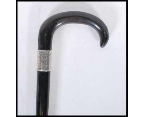 A early 20th Century 1920's silver collared promenade walking stick cane having horn crook handle with ebony tapering shaft a