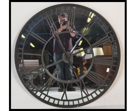 A large contemporary ebonised iron framed skeleton wall clock, mirrored backed and iron roman numeral chapter ring fitted wit