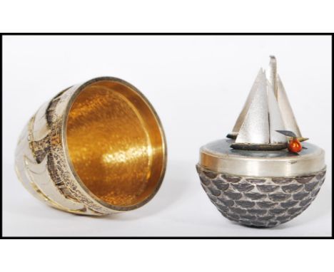 A silver hallmarked Stuart Devlin limited edition surprise egg having a textured exterior depicting ships and waves opening t