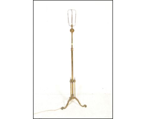 An early 20th Century Edwardian brass adjustable telescopic standard lamp being raised on three scrolled legs having a centra