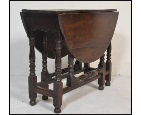 An 18th century country oak drop leaf dining table. Raised on gun barrel supports united by stretchers having gate leg action