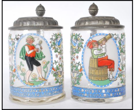 A pair of early 20th Century German glass and enamel over painted steins. Each with fitted pewter hinged lids&nbsp; having a 