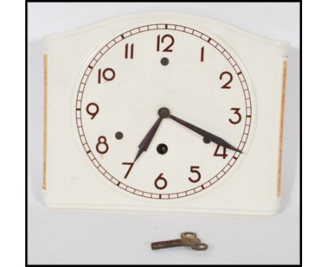 An early 20th Century Art Deco ceramic wall clock having a round face with arabic numerals to the chapter ring with brown pai