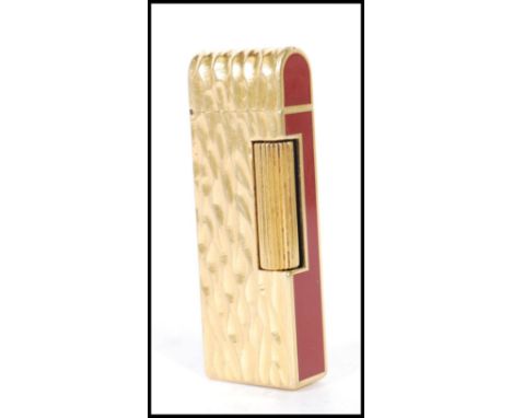 A vintage Dunhill cigarette lighter having burgundy enamelled panels to the ends with a gilt bark effect and domed top. Measu