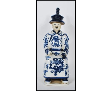 A Chinese blue and white glazed ceramic figurine of a seated Chinese gentleman in a robe smoking an opium pipe. Chinese chara