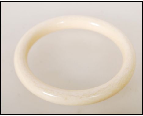 A late 19th / early 20th Century ivory bangle of typical circular form. Interior measures approx 6.6cm diameter.