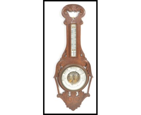An early 20th Century 1920's oak cased Aneroid barometer having carved scroll work. Set with a white ceramic drop dial and op