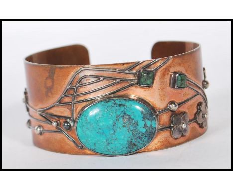An early 20th Century Arts and Crafts bangle bracelet having a copper body with applied silver floral and geometric decoratio