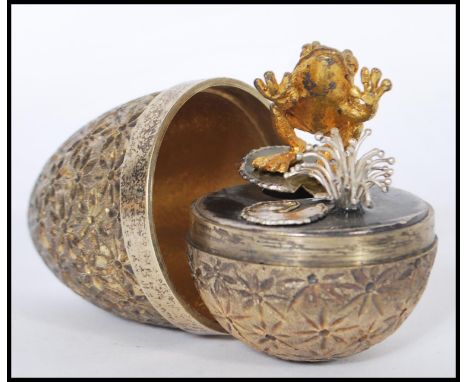A silver hallmarked Stuart Devlin silver limited edition surprise egg having a stylised floral textured exterior opening to r