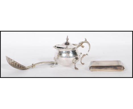 A silver hallmarked mustard pot condiment having a scrolled handle and floral garland rim, being raised on three gadrooned fe
