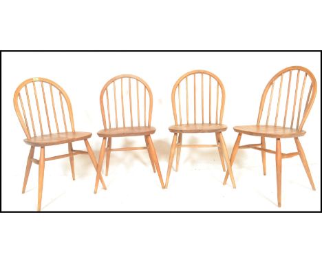 A set of four mid 20th century Ercol Windsor Quaker style hoop-back dining chairs in light elm and beech construction being r