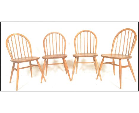 A set of four mid 20th century Ercol Windsor Quaker style hoop-back dining chairs in light elm and beech construction being r