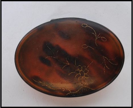 A 19th Century Georgian tortoise shell patch box of oval form having gilt floral inlay to the lid.&nbsp;Measures: 8cm x 6cm.