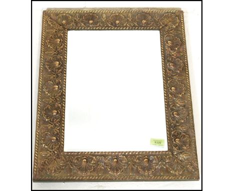 An early 20th Century wall mirror of rectangular form having an embossed brass frame with scallop shell design together with 