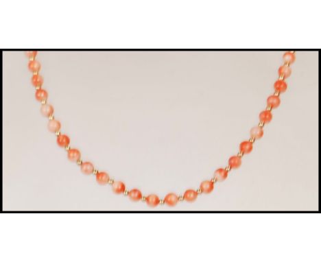 A vintage coral beaded necklace having a 9ct gold spring ring clasp with gold tone spacer beads. Clasp stamped 375. Measures 