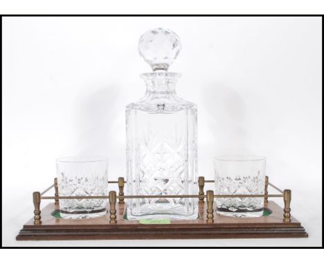 A vintage 20th Century cut glass decanter set having a stepped wooden base with a cut glass decanter of square form with two 