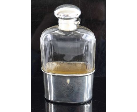 A George V pocket hip flask, having a facet cut clear glass body with silver bayonet cap and removeable silver cup, maker Asp