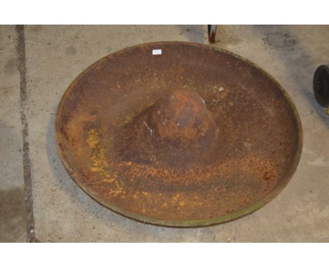 A large circular cast iron pig trough