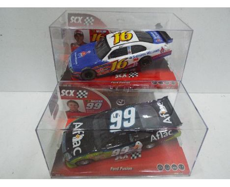 SCX - 2 x Slot Cars in 1:32 scale. Both Ford Fusion's, models are # 63950 and # 64120. Vehicles appear mint in perspex presen