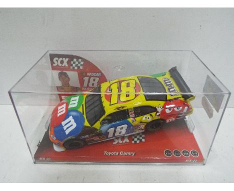 SCX - Slot Car in 1:32 scale. # 64130 Toyota Camry. M and M's branding. Vehicle appears mint in perspex presentation cases. L