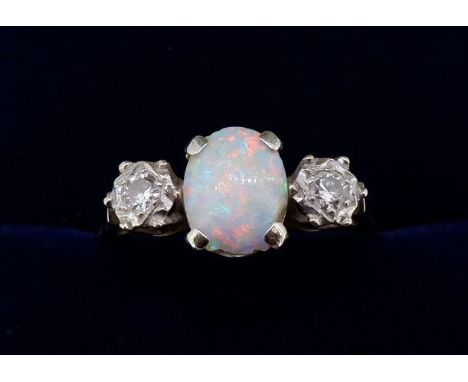 An 18 carat gold and platinum set opal ring, the oval cut opal flanked by two illusion set diamonds, size N (opal chipped) 