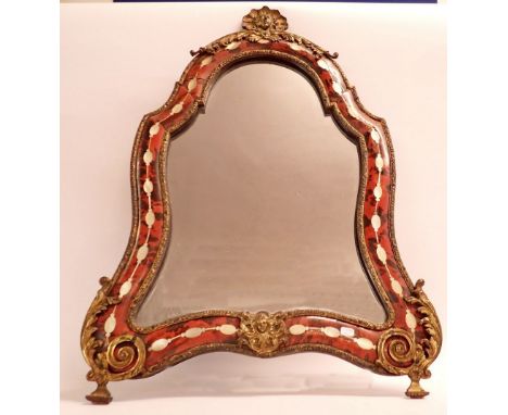A 19th century tortoiseshell and mother of pearl shield form mirror with gilt metal mounts and shell framed mask surmount, 60