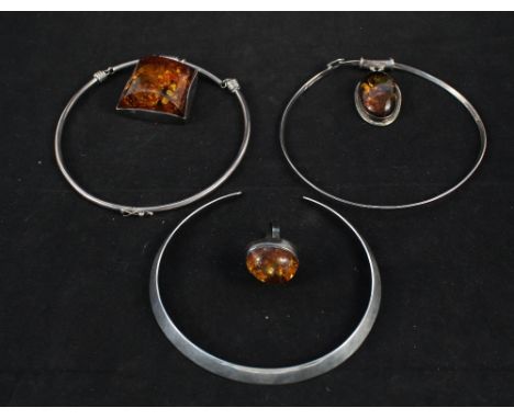 Three silver choker necklaces, two with large amber pendants and a silver ring set with a large amber stone