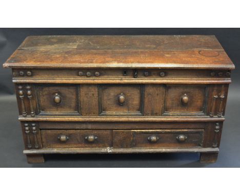 A 17th century oak block front mule chest, hinged top above a three-panel front applied with geometric mouldings, split-turni