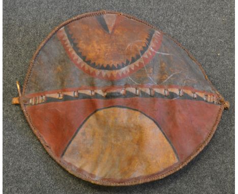Tribal Art - a leather shield geometrically decorated in red, white and black, 87cm long