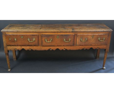 An 18th century oak low dresser, with three deep short mahogany crossbanded drawers, shaped apron, later brass swan neck hand