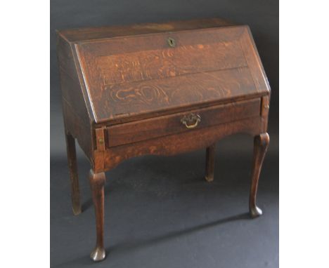 A George II oak bureau, fall front enclosing a cupboard, niches and small drawers, above a single long frieze drawer and a wa
