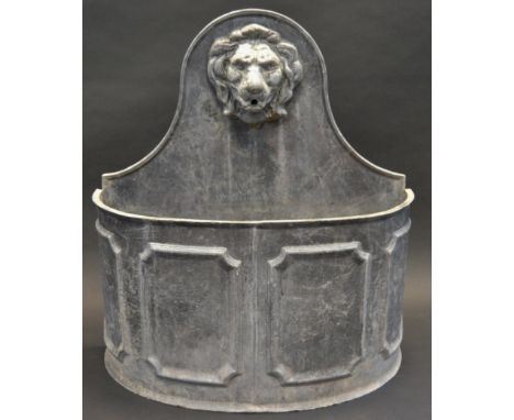 A substantial lead bow fronted water fountain, the arched back with lion mask, demi-lune trough, 74cm high, 68cm wide