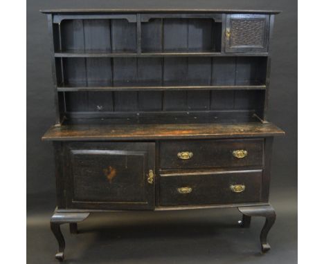 A late Victorian oak dresser, outswept cornice above a small glazed door and an arrangement of shelves, the projecting base w