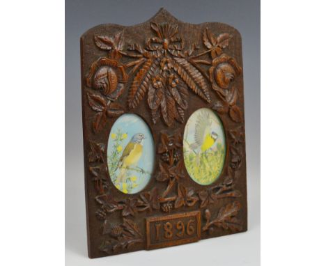 A Victorian shield shaped easel photograph frame, carved with roses, thistles and oak leaves, with two oval apertures, dated 