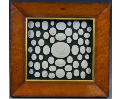 An arrangement of plaster intaglios, mostly profile portrait medallions, 21.5cm x 23.5cm, maple frame