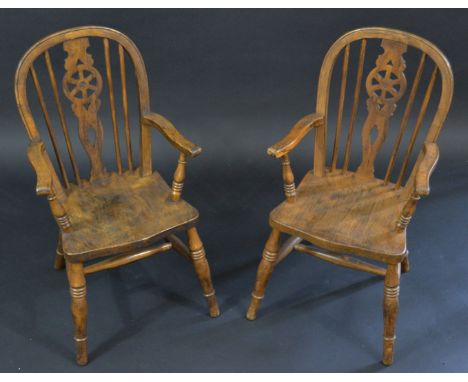 A pair of child’s Windsor elbow chairs, arched stick backs with shaped and pierced wheel splats, outswept arms, saddle seats,